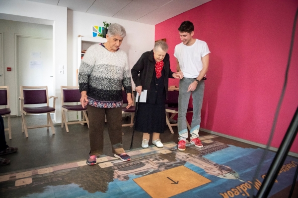 Illustration d’une séance réalisée par des seniors. Ici, deux personnes s’entraînent au passage du pas en dansant en rythme, tout en répondant à des questions.
