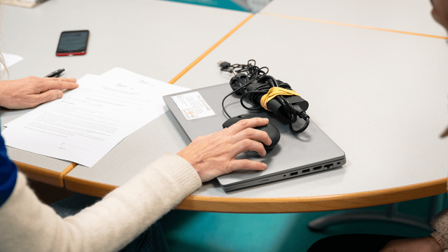 Remise d’un kit informatique reconditionné à un étudiant : un ordinateur portable, sa souris et son chargeur sont posés sur la table tandis qu’une personne signe les documents de mise à disposition.